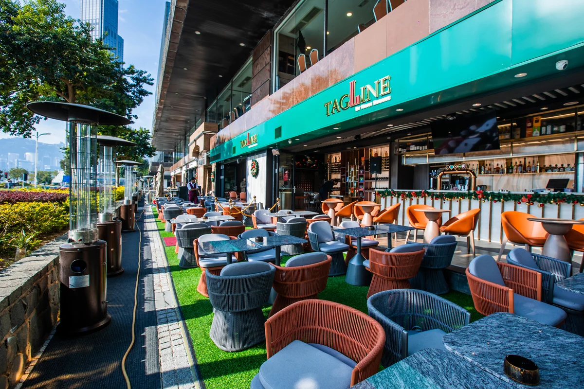 Tagline’s patio on the promenade: rattan chairs, tables and outdoor heaters under the green Tagline sign