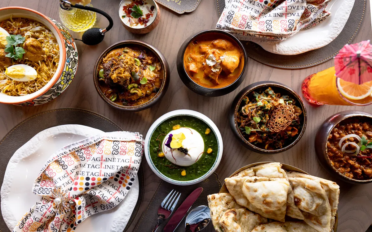 An overhead spread of curries, biryani, naan and Tagline napkins