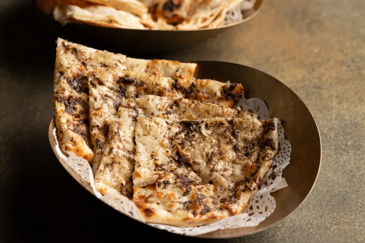 Truffle cheese naan in a brass bowl lined with a paper doily